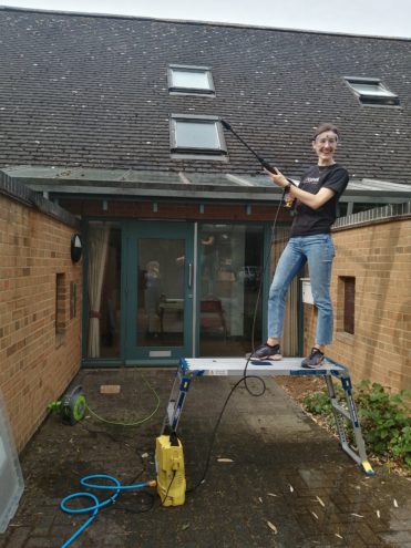 lady power washing a roof